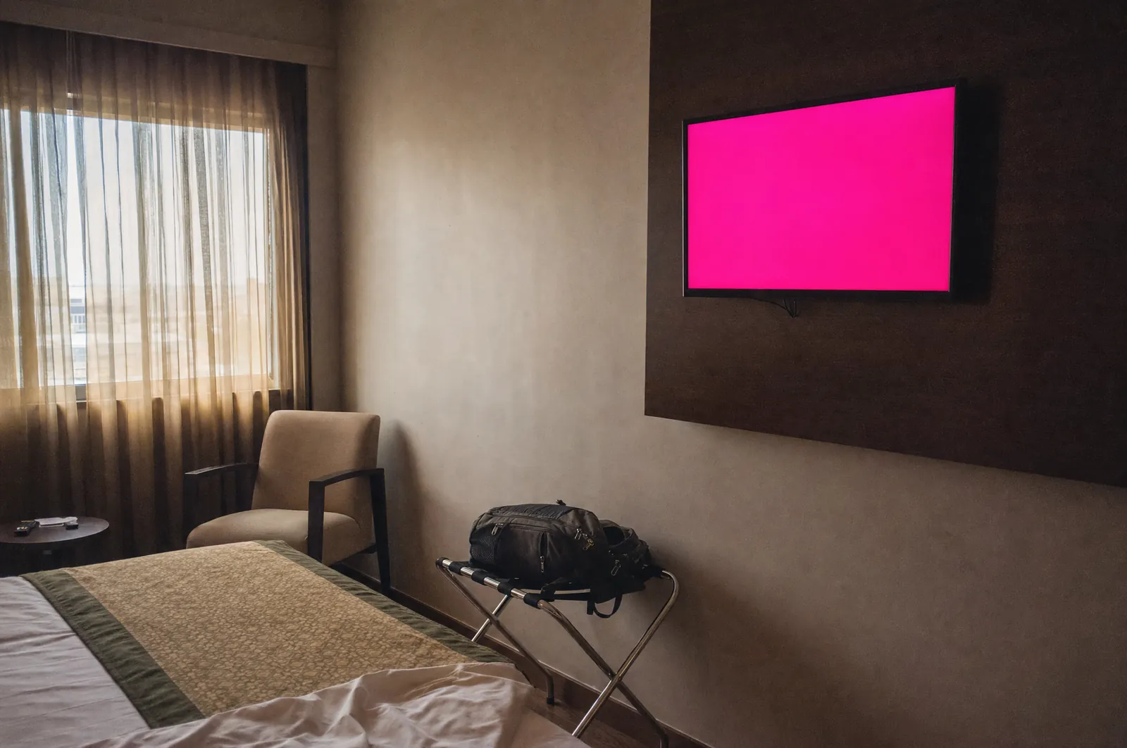 Quarto de hotel com TV acesa em cor sólida